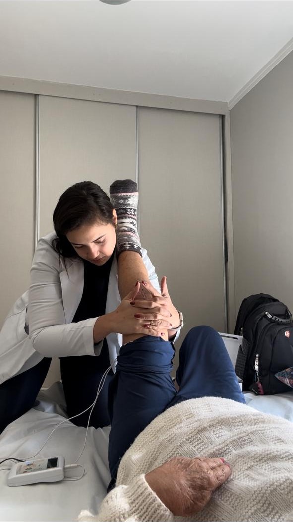 Bruna Kramer realizando fisioterapia domiciliar em Campinas, aplicando eletroterapia em paciente