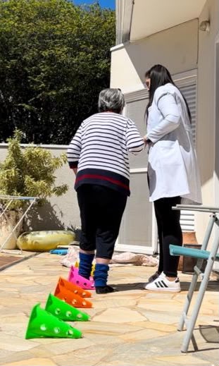 Bruna Kramer conduzindo treino de marcha e equilíbrio com paciente na reabilitação pós-operatória